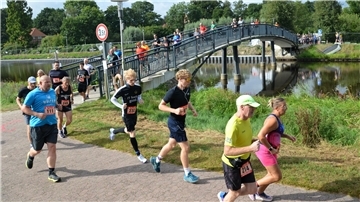 Läuferinnen und Läufer passieren eine Brücke.