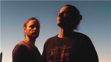 Jonah-Weihnachtskonzert in Brake: Indie-Duo spielt in St. Marien Zwei in Sonnenschein getauchte Männer stehen vor einem blauen Himmel.