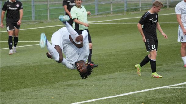 Ein Fußballspieler vollführt einen Vorwärtssalto auf dem Platz.