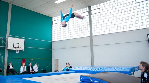 Ein Mädchen turnt einen Salto auf dem Trampolin.