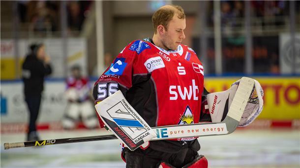 Ein Eishockey-Torwart steht auf dem Eis und nimmt seinen Schläger unter die Lupe.