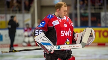 Ein Eishockey-Torwart steht auf dem Eis und nimmt seinen Schläger unter die Lupe.