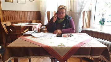 Eine Frau an einem Tisch. Vor ihr Unterlagen.
