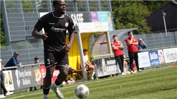 Ein Fußballer im schwarzen Trikot ist am Ball.
