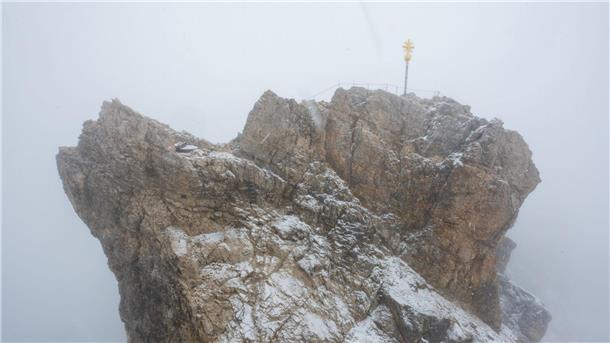 Bergnot: Bergsteiger im Schneetreiben an Zugspitze gerettet Nebelwolken umhüllen bei Schneetreiben auf der Zugspitze die Aussichtsplattform mit dem Gipfelkreuz (Archivbild). Aus mehreren Bergsteigergruppen wurden Notrufe abgesetzt, nachdem sie aufgrund von Witterung und Neuschnee auf etwa 2500 Metern Höhe nicht mehr weiterkamen.