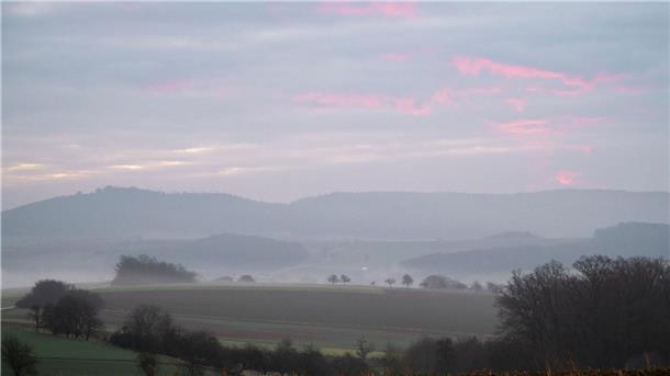 Bilder des Tages Neblige bayerische Landschaft mit Morgenrot am Himmel.