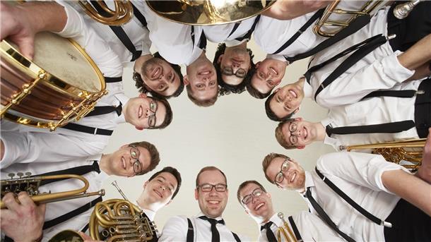 Die Musiker von „Salaputia Brass“ stehen im Kreis und blicken nach unten in die Kamera