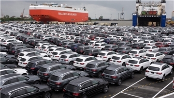 Autos parken im Hafen vor Schiffen.