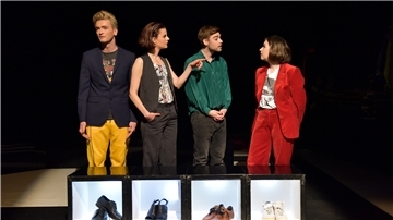 Vier Schauspieler stehen vor Schuhen und unterhalten sich angeregt.