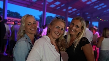 Drei Frauen lächeln auf der Mittsommernachtsparty in Bramel in die Kamera.