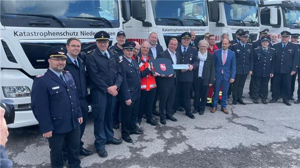 Feuerwehrleute und Niedersachsens Innenminister Boris Pistorius stehen vor Lastwagen.