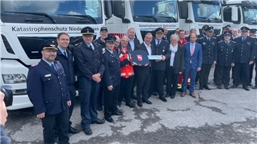 Feuerwehrleute und Niedersachsens Innenminister Boris Pistorius stehen vor Lastwagen.
