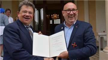 Zwei Männer mit der Urkunde für das Bundesverdienstkreuz