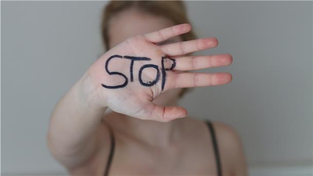 Eine junge Frau zeigt ihre Hand, auf der das Wort STOP steht.