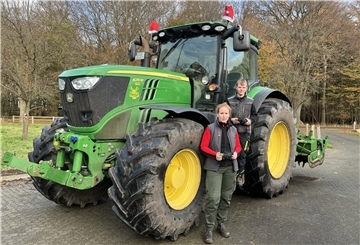 Eine Frau und ein Mann stehen vor einem Trecker.