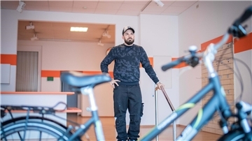 Ein Mann steht in einem Raum. Vor ihm ein Fahrrad.