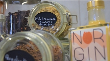 Verschiedene Kräuter werden in Glasbehältern gelagert. Im Vordergrund steht die Norgin-Flasche Eierlikör mit Rum. 