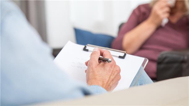 Eine Patientin sitzt mit ihrem Psychotherapeuten in einem Behandlungsraum.