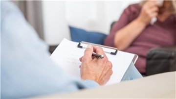 Eine Patientin sitzt mit ihrem Psychotherapeuten in einem Behandlungsraum.