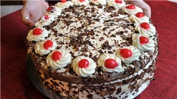  Eine Schwarzwälder Kirschtorte, bestehend aus weißer Sahne, roten Kirschen, schwarzbraunem Biskuitboden und dunkler Schokolade