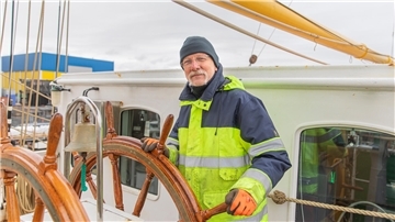 Ein Mann steht am Steuer der "Alex II". Oberbootsmann Flo Bertzbach aus Bremen ist momentan Chef der Werft-Crew der „Alexander von Humboldt II“.