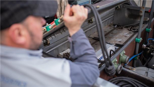 Sie sind die „Erste-Hilfe-Spezialisten“ für alles, was im Hafen rollt Oberfahrer Vadim Trofimov zeigt auf der Ladefläche seines Fahrzeuges die Batterien, welche benötigt werden, um liegen gebliebene Fahrzeuge auf dem Autoterminal mit frischer Energie zu versorgen.