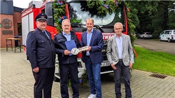 Vier Männer stehen vor einem Feuerwehrfahrzeug