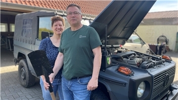 Ein Paar steht vor einem Jeep.
