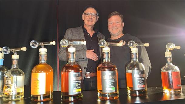 Auf dem Bild zu sehen ist Oliver "Mo" Morawietz (54) mit dem Cloppenburger Whiskyproduzent Jens Lübbehusen. Im Vordergrund verschiedene Whiskyflaschen auf einer Theke.