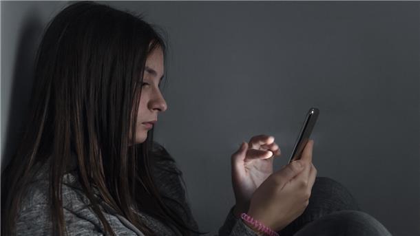 Ein Mädchen schaut auf ihr Mobiltelefon. 