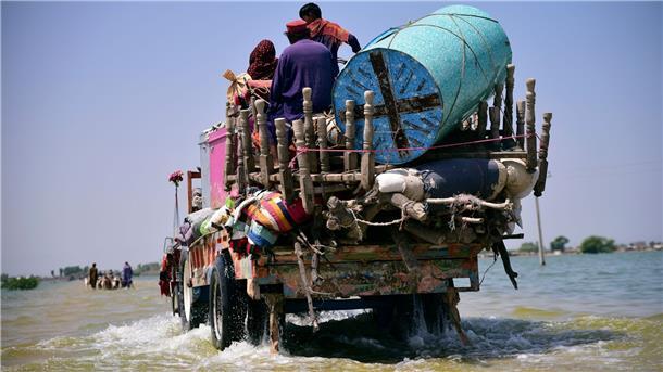 Opfer von Überschwemmungen durch Monsunregen tragen Habseligkeiten aus ihrem überfluteten Haus in der Provinz Sindh.