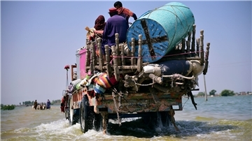 Opfer von Überschwemmungen durch Monsunregen tragen Habseligkeiten aus ihrem überfluteten Haus in der Provinz Sindh.
