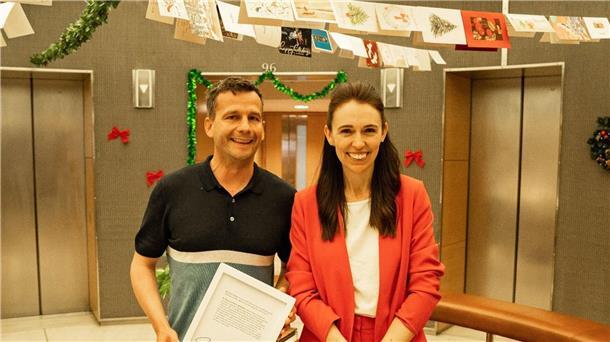 Ardern sammelt mit „arroganter Pimmel“-Kommentar Spenden Oppositionspolitiker David Seymour und Neuseelands Premierministerin Jacinda Ardern posieren mit einem unterzeichneten Ausdruck Protokolls, in dem Ardern Seymour beleidigt.