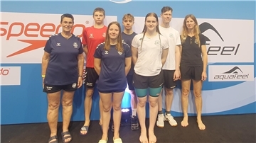 Schwimmerinnen und ihre Trainerinnen lächeln in die Kamera.
