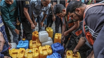 Palästinenser stehen in Rafah Schlange, um an Wasser zu gelangen.