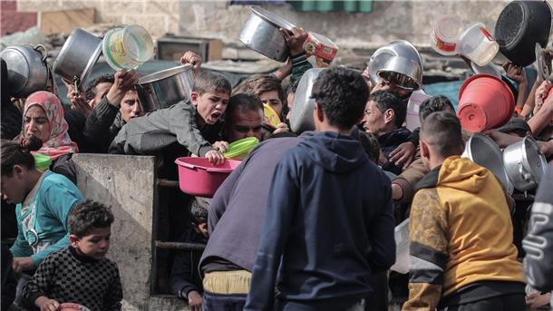 Palästinenser warten an einer Spendenstelle in einem Flüchtlingslager im südlichen Gazastreifen auf Lebensmittel.