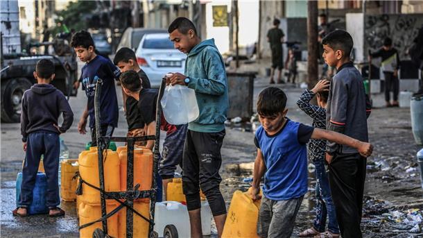 „Obdachlose ohne Zukunft“ in Gaza Palästinensische Kinder stehen mit Wasserbehältern Schlange, um sie mit Trinkwasser zu füllen.