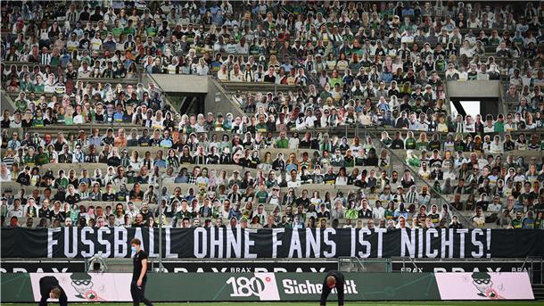 Pappaufsteller stehen statt der Fans auf der Tribüne, an der ein Banner mit der Aufschrift „Fussball ohne Fans ist nichts!"