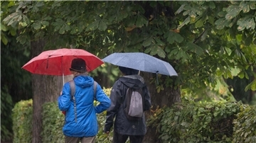 Passanten mit Regenschirmen in Moritzburg in Sachsen.
