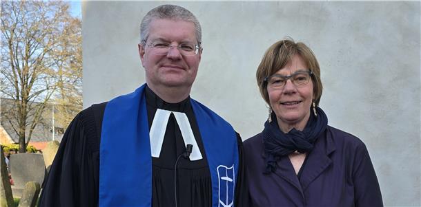 Ein Mann, der evangelischer Pfarrer ist, und eine Seemannsdiakonin stehen vor einer Kirche.