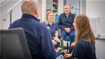 Patient Wolf-Dieter Seifert wird von Pia Henke (links) und Alexandra Lapp physio- und ergotherapeutisch versorgt. Gemeinsam arbeiten sie daran, dass Seifert bald ohne Rollator laufen kann. 