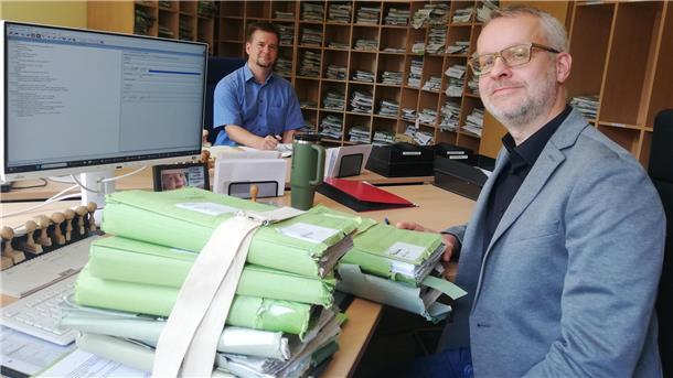 Aktenberge sollen schrumpfen: Das Amtsgericht stellt sich digital auf Zwei Männer an Schreibtischen mit Aktenbergen auf dem Schreibtisch