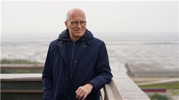 Ein Mann steht an der Mole. Die Nordsee im Hintergrund.