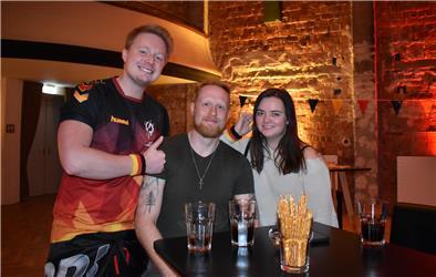 Drei Fußballfans lächeln in die Kamera.