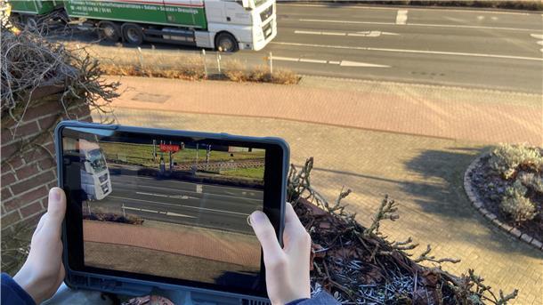 Eine Person filmt mit dem Ipad eine Straße.