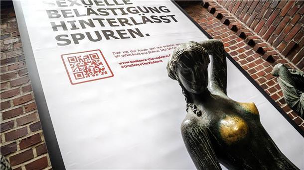 Bronze-Statuen als Zeichen gegen sexuelle Belästigung Plakat mit der Aufschrift „Sexuelle Belästigung hinterlässt Spuren“ hinter der Bronzeskulptur „Jugend“ von Bernhard Hoetger in Bremen.