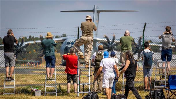 Planespotter stehen an einem Zaun vor dem Fliegerhorst Wunstorf und fotografieren einen Airbus A400M der Luftwaffe.