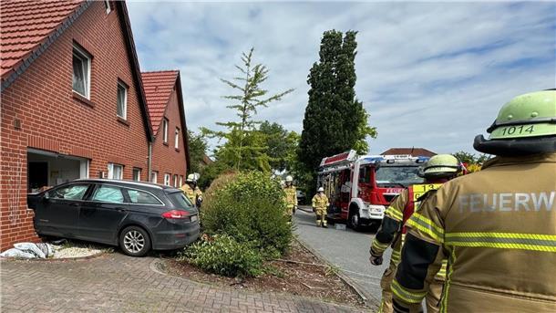 Ein Auto hat eine Hauswand durchbrochen, drumherum stehen Feuerwehrleute.