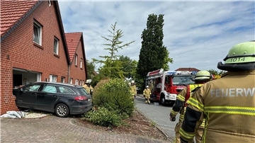 Ein Auto hat eine Hauswand durchbrochen, drumherum stehen Feuerwehrleute.