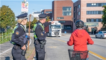 Zwei Polizisten weisen eine Radfahrerin auf ihren Fehler hin. 
